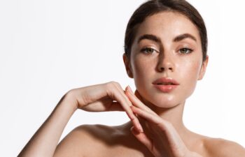 Beauty. Woman 25 years, has shiny glowing skin, clean nourished body and face, looks sensual at camera, eyebrows sick with brow gel, white background